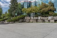 several trees outside of a large office building with rocks around the building's sides