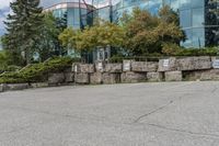 several trees outside of a large office building with rocks around the building's sides