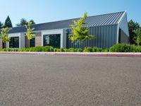 empty parking lot with white and gray building in the background with grass and trees outside