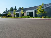 empty parking lot with white and gray building in the background with grass and trees outside