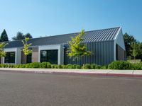 empty parking lot with white and gray building in the background with grass and trees outside