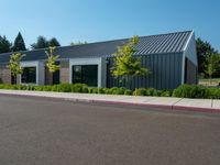 empty parking lot with white and gray building in the background with grass and trees outside