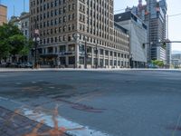 the green paint is painted on a bike path in front of an office building and large, trees