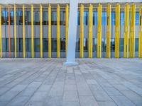 a concrete structure made into rows of orange and yellow poles are on a cement sidewalk