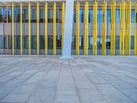 a concrete structure made into rows of orange and yellow poles are on a cement sidewalk