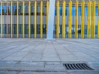 a concrete structure made into rows of orange and yellow poles are on a cement sidewalk