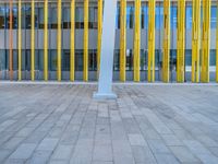 a concrete structure made into rows of orange and yellow poles are on a cement sidewalk