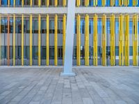 a concrete structure made into rows of orange and yellow poles are on a cement sidewalk