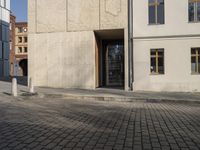 a person with a suitcase walking across an outside courtyard in front of a building,