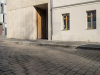 a person with a suitcase walking across an outside courtyard in front of a building,