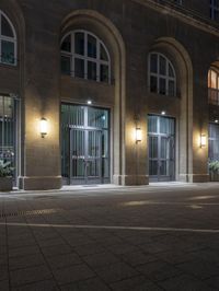 there are several lights on the street outside of the building at night time with no people around