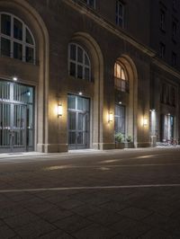 there are several lights on the street outside of the building at night time with no people around