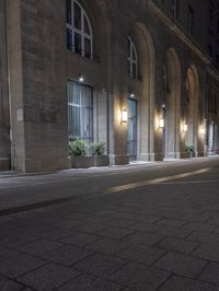 there are several lights on the street outside of the building at night time with no people around