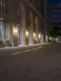 there are several lights on the street outside of the building at night time with no people around