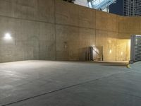 a sidewalk area in front of a huge, concrete wall at night with lights shining