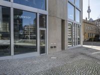 a building with a big open door and two men walking down the street while carrying umbrellas