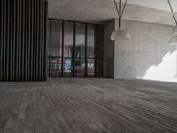 a big wooden floor next to a building with some glass windows and lighting fixtures hanging