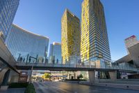 two highrise buildings are in the foreground and a pedestrian bridge overpass between them