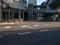 an empty road with a street sign at the curb in front of an office building