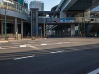 an empty road with a street sign at the curb in front of an office building