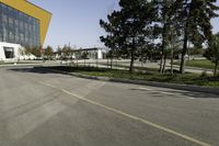 empty street with yellow building and trees in the background behind it - some people crossing the road