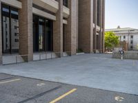 a street with a building near the building in the middle and on the left of which is a parking lot, as shown in this photo