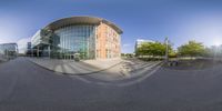 a fisheye lens of people walking outside a building at an office park area with a bench in front