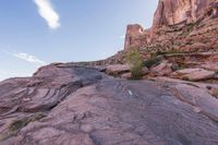 a trail is winding down a mountain, which is surrounded by rock formations and large boulders