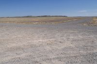 a dry area with some dirt and rocks in the sand below a blue sky,