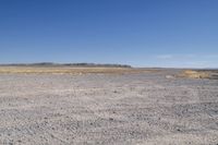 a dry area with some dirt and rocks in the sand below a blue sky,