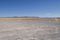 a dry area with some dirt and rocks in the sand below a blue sky,