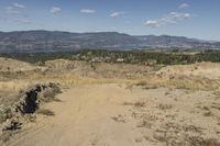 there is a bike rider on a paved dirt road through rocky area near a mountain