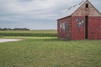 an old brick building sitting in the middle of a field with a cow painted on it