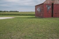 an old brick building sitting in the middle of a field with a cow painted on it