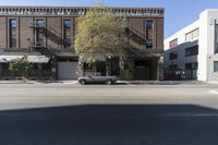 an old brick building with a car parked on the street in front of it is a commercial area next to the large warehouse