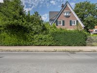 an old brick home with lots of greenery in front of it and the gate is locked to the road