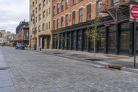 an old brick sidewalk and street next to buildings and a fire hydrant in the middle