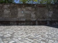 an old brick wall with a blue sign on the back of it in the middle of a paved street