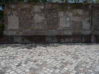 an old brick wall with a blue sign on the back of it in the middle of a paved street