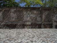 an old brick wall with a blue sign on the back of it in the middle of a paved street