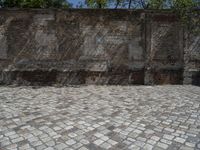 an old brick wall with a blue sign on the back of it in the middle of a paved street