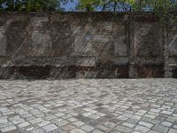 an old brick wall with a blue sign on the back of it in the middle of a paved street