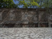 an old brick wall with a blue sign on the back of it in the middle of a paved street