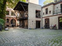 an old bricked building with many bikes parked in the courtyard, and windows to see inside