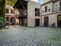 an old bricked building with many bikes parked in the courtyard, and windows to see inside