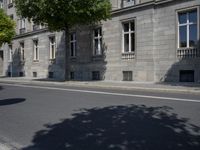 this is an old building on a street corner next to a road with trees and bushes on either side
