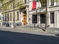 the red bus is parked on the side of the road in front of an old building