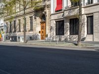 the red bus is parked on the side of the road in front of an old building