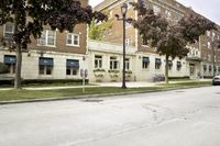 an old building on a city street that has trees and grass in it's front