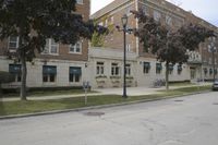 an old building on a city street that has trees and grass in it's front